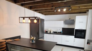 Una cucina moderna con isola centrale, mobili bianchi, piano di lavoro nero e forno integrato.