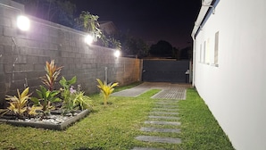 A well-maintained garden with a stone pathway leading to a gated entrance. - Villa CAPUCINE with heated saltwater pool - Saint-Gilles-les-Bains (Saint-Paul)
