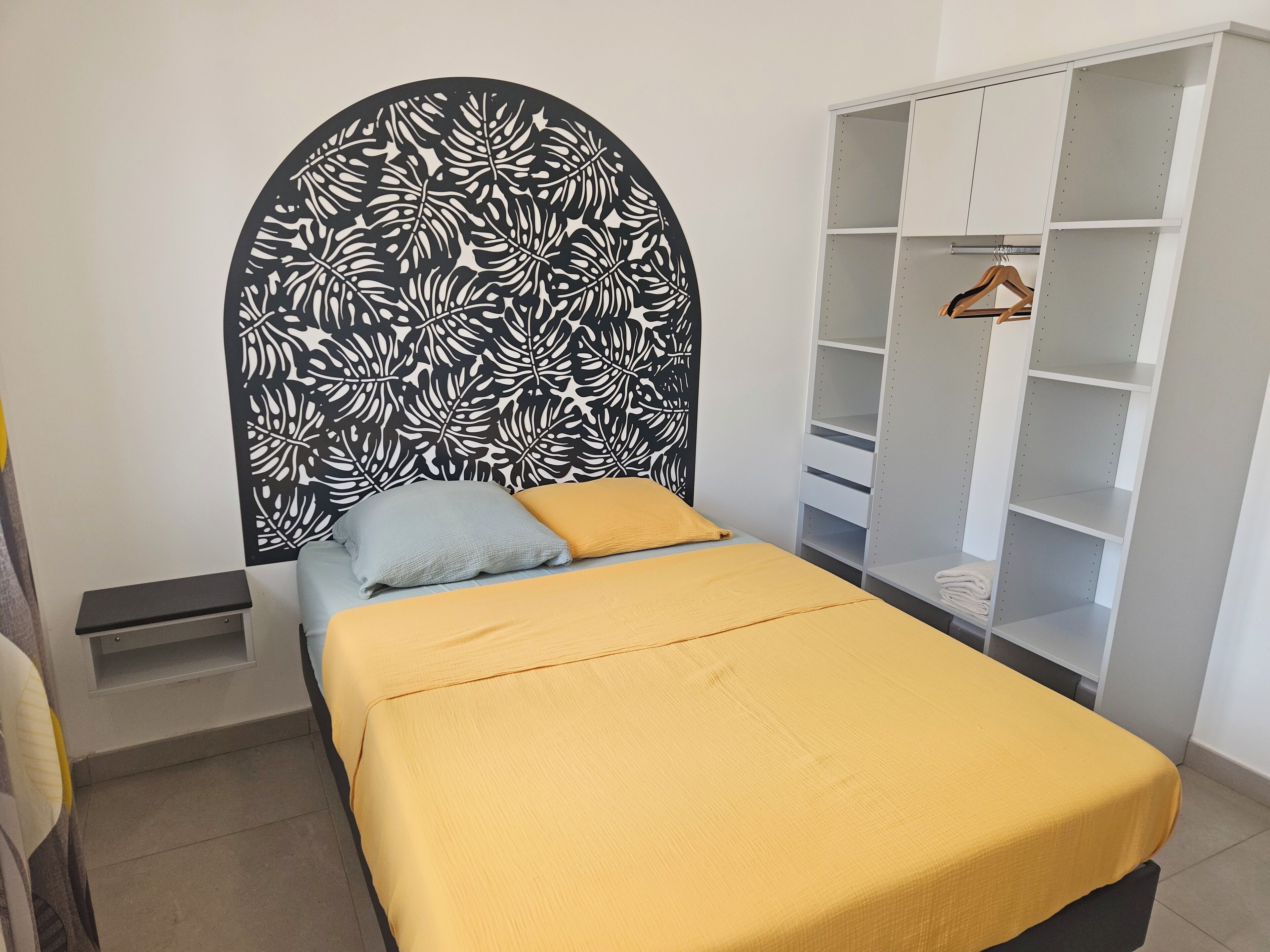 A bedroom with a bed, a wardrobe, and a nightstand.