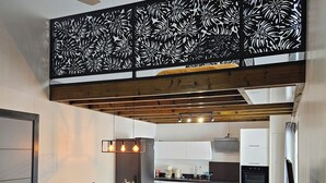 Una cucina moderna con mobili bianchi, un piano di lavoro nero e un soffitto in legno.