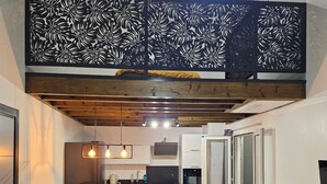 Una cucina moderna con mobili bianchi, un piano di lavoro nero e un forno integrato. C'è una zona pranzo con un divano in pelle nera e una sedia bianca.