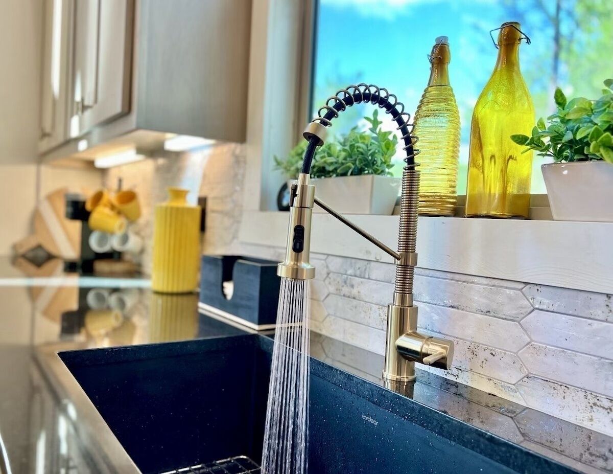 A kitchen with a modern faucet, a sink, and a window with a view of greenery.