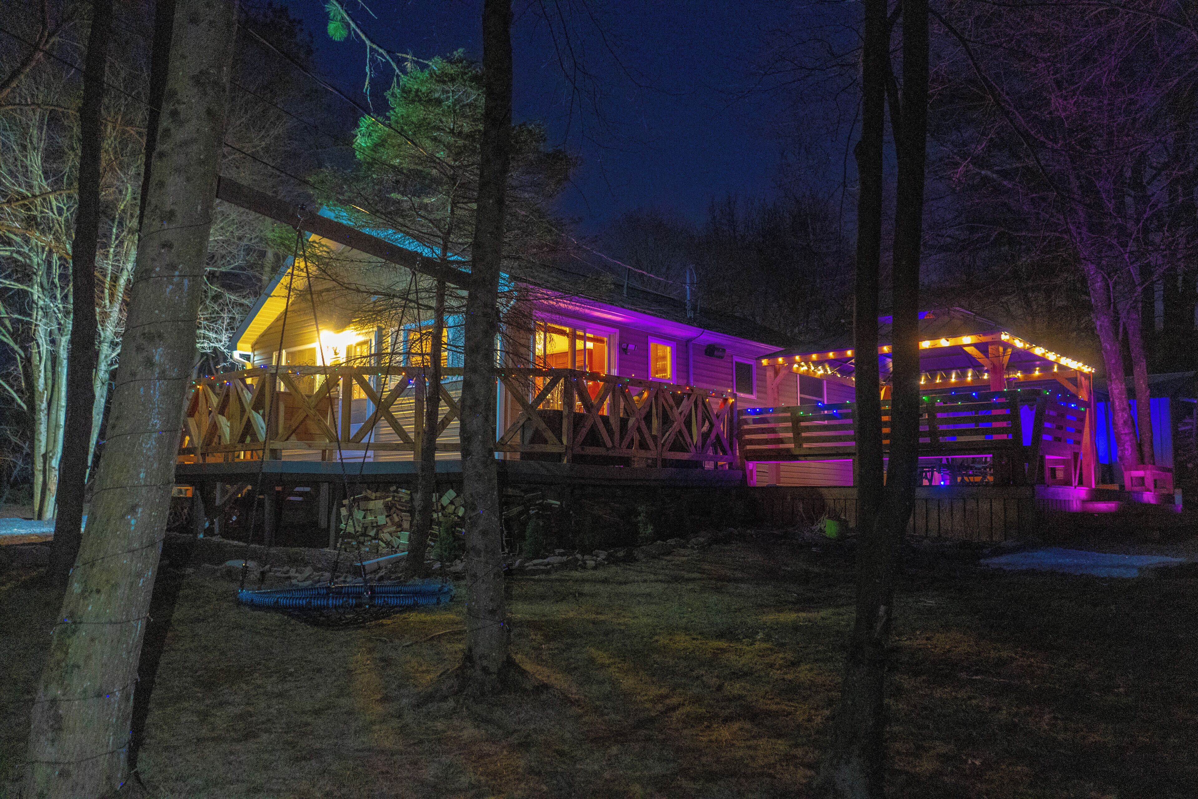 A wooden cabin with a deck, surrounded by trees.