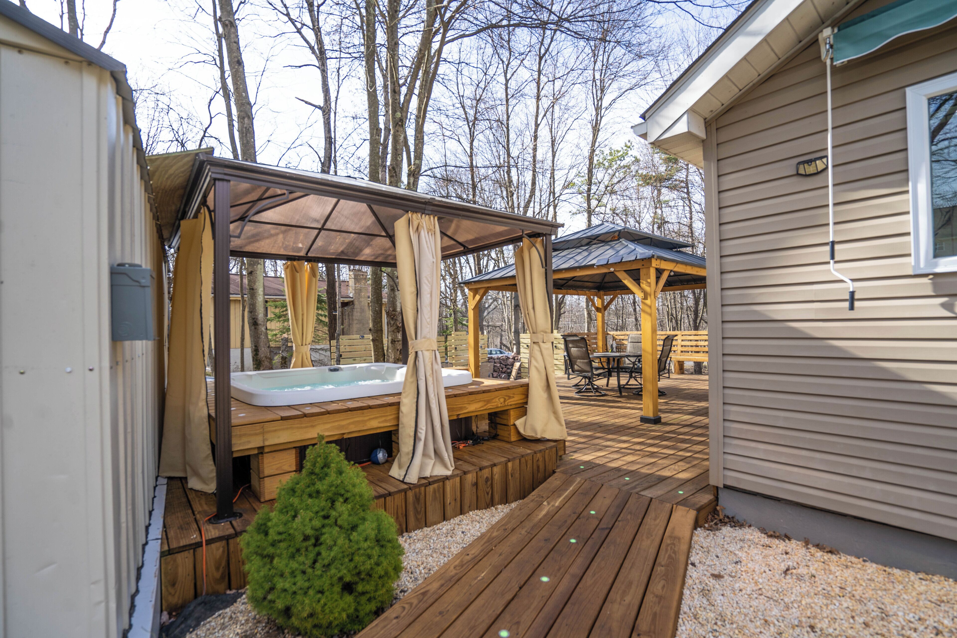 Une terrasse en bois avec un jacuzzi et un espace salon abrité.