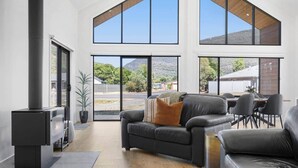 A spacious living room with a modern fireplace, large windows offering a view of the outdoors, and a comfortable seating area.