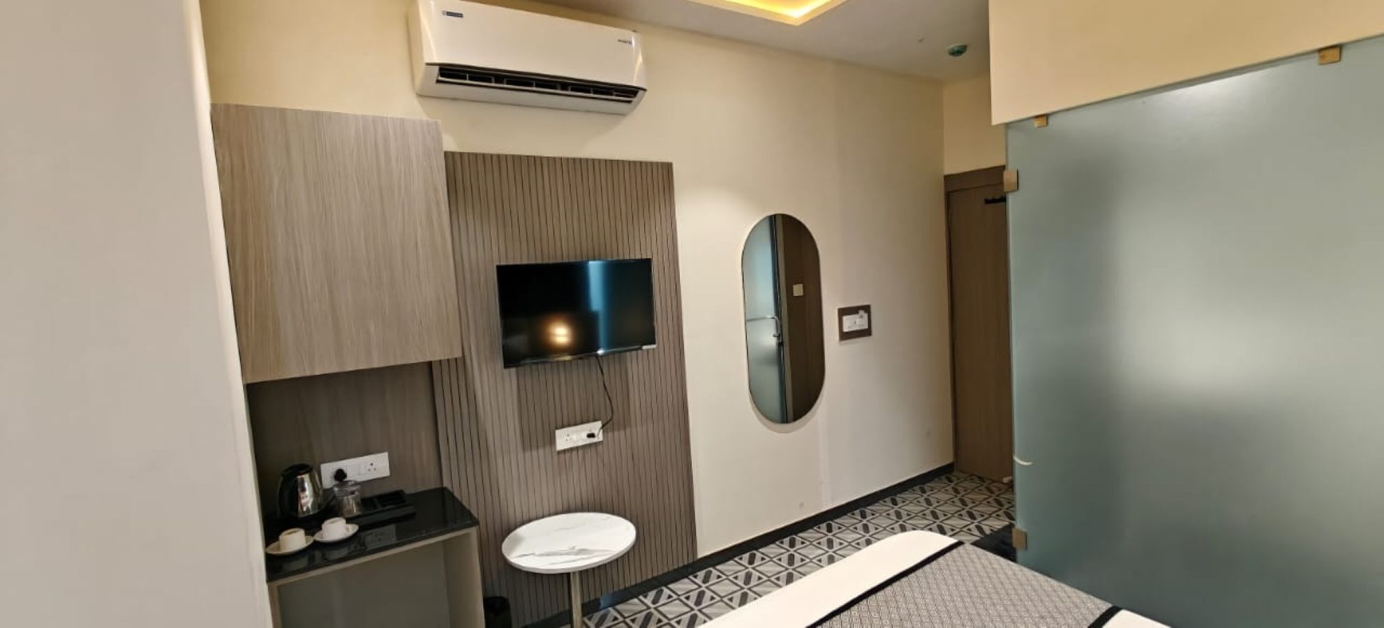 Un baño moderno con una televisión de pantalla plana, un espejo redondo, un lavamanos y un inodoro.