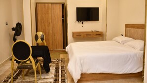 Una camera da letto con un letto, un comodino, una televisione e un'armadio in legno.