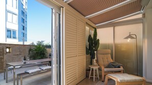 A modern living room with a glass door leading to a balcony, a sofa, a small table, and a chair.