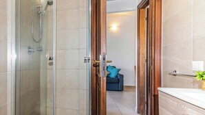 A bathroom with a glass shower enclosure, a wooden door, and a white countertop with a plant. - Le Case Della Cinta Hosue (San Teodoro)