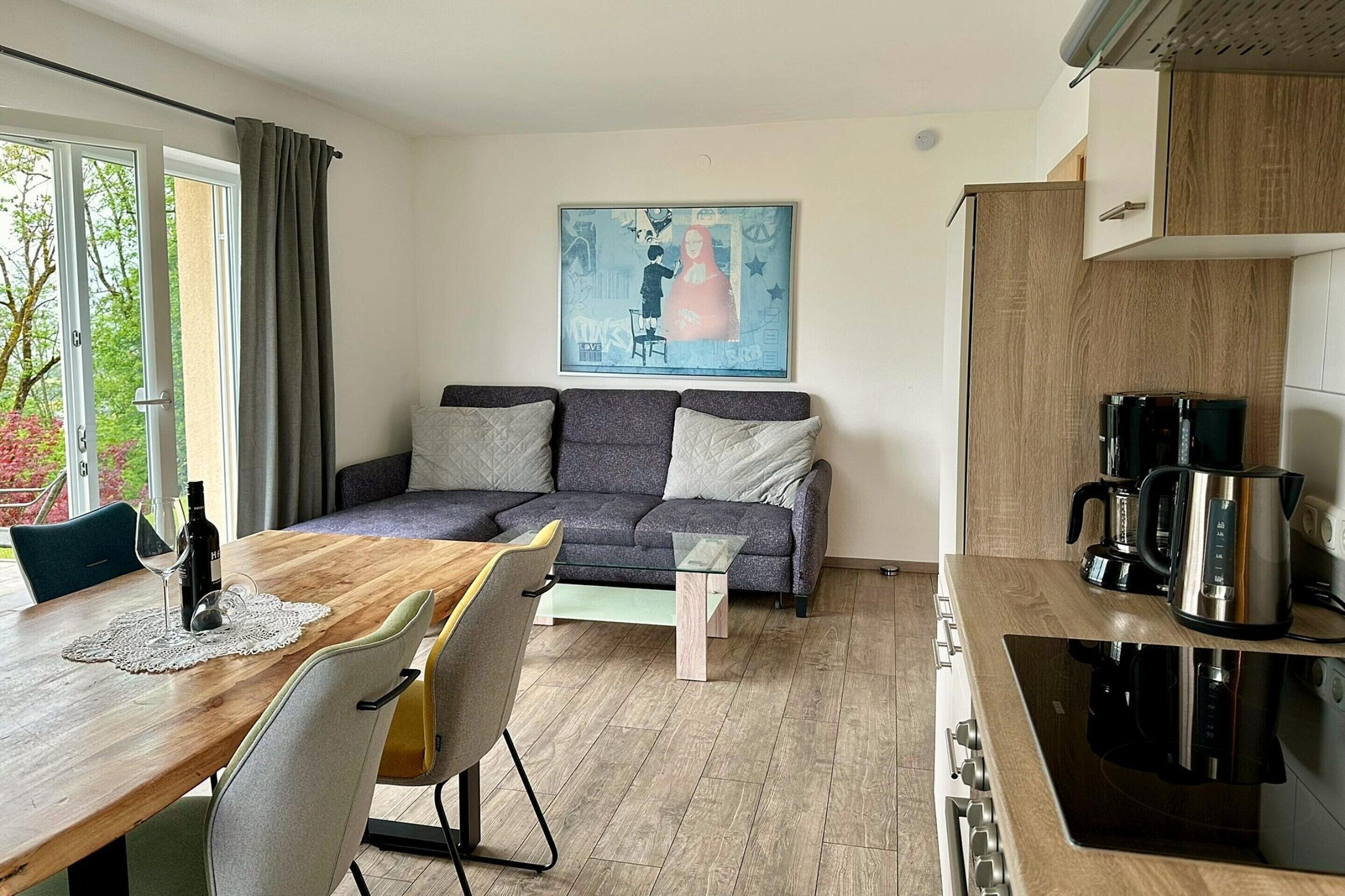 A modern living space with a dining area, sofa, and kitchen.