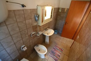 Un baño con inodoro, bidé, lavabo y un mueble de espejo.