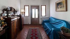 A living room with a wooden ceiling, a blue sofa, a wooden cabinet, and a door with windows. - Farmhouse in Tuscany With Pool & Valley Views (Poppi)