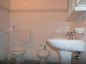 Une salle de bain équipée de toilettes, d’un bidet et d’un lavabo.