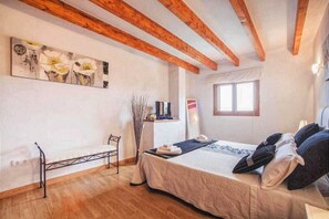 Un dormitorio con cama, un banco, una ventana y obras de arte en la pared.