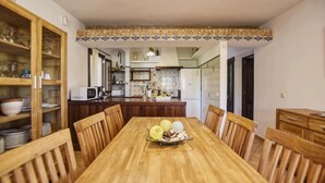Un coin repas avec une table en bois, des chaises, une cuisine en arrière-plan et une bordure décorative en carreaux au-dessus du comptoir.