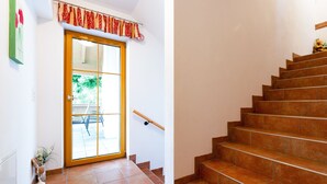 Un escalier avec une main courante en bois et une porte dotée d’un panneau de verre et d’une imposte rouge à motifs.