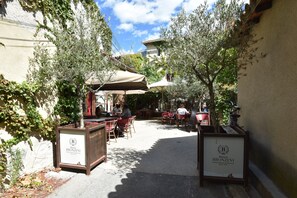 An outdoor café area with tables and chairs, surrounded by greenery and architectural elements. - Villa Alba: Sunlit Comfort in Lirac (Tavel)