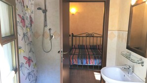 Un bagno con doccia, un letto e un lavandino.
