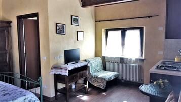 Ein gemütliches Zimmer mit einem Bett, einem Schreibtisch mit Computer, einem Stuhl, einem Fenster und einer Küchenzeile.