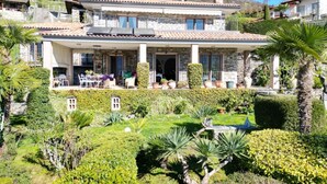 Ein zweistöckiges Haus mit Terrasse, umgeben von gepflegten Gärten und einem Pool.
