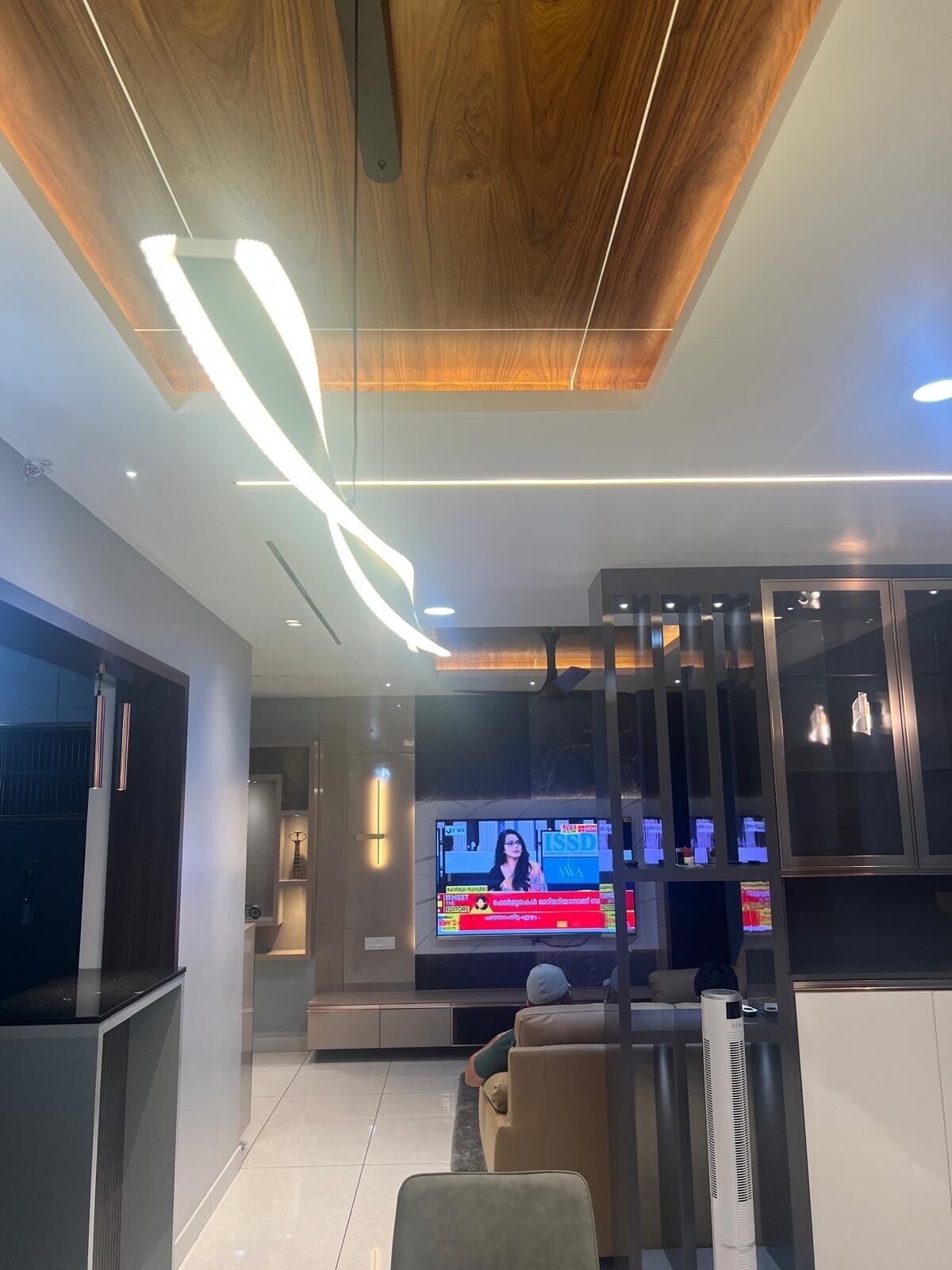 A modern living room with a flat-screen TV, comfortable seating, and a wooden ceiling.