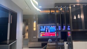 A modern living room with a flat-screen TV, comfortable seating, and a wooden ceiling. - 3-bedroom 3 bath Luxury apartment in serene Thiruvananthapuram (Thiruvananthapuram)