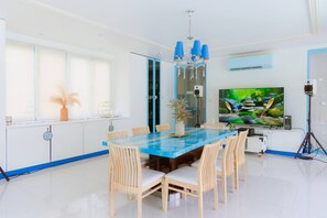 A modern dining area with a blue marble table, white chairs, and a chandelier. - Private Pool Party Villa Games & Karaoke, (Pak Kret)