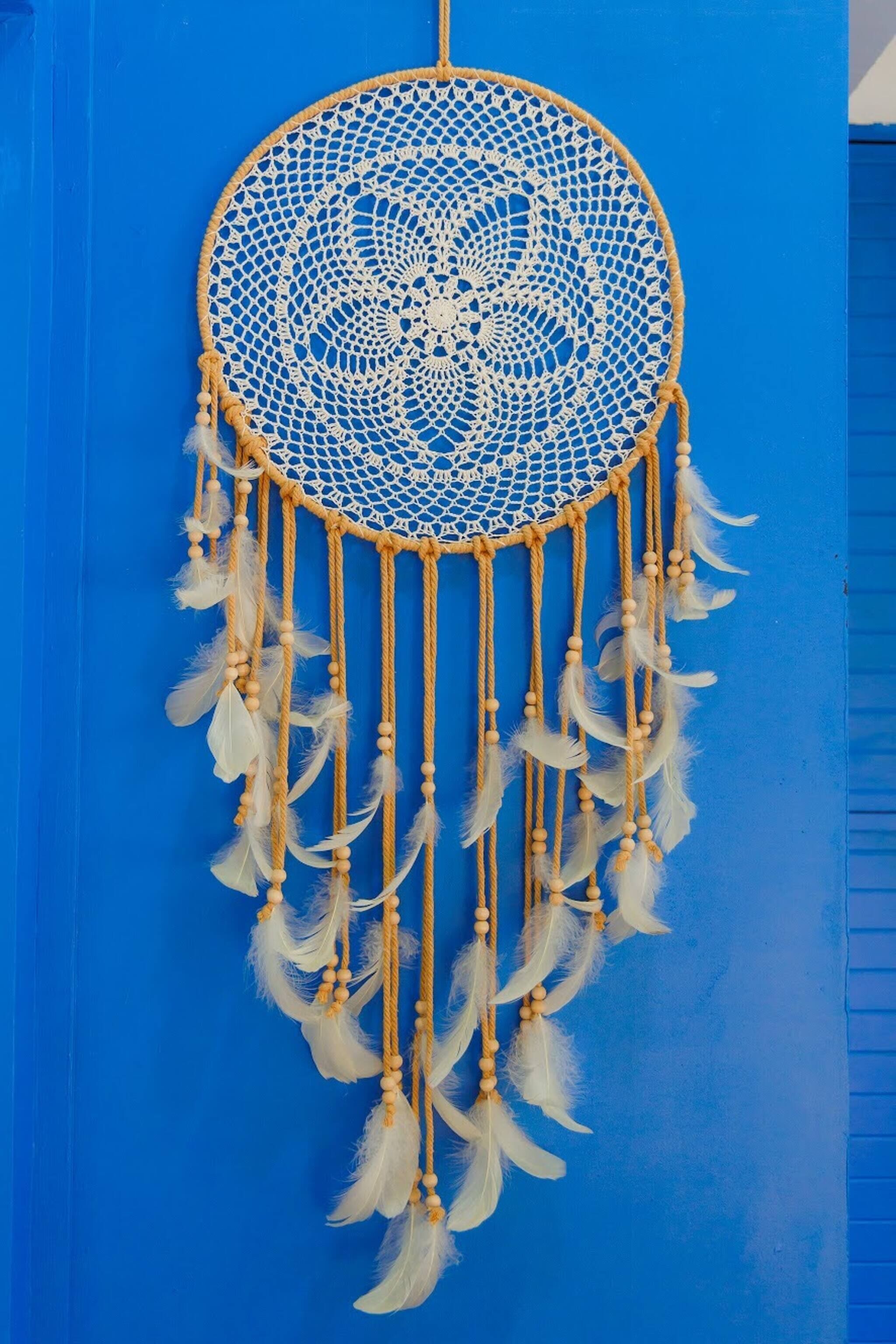 Un sogno catturato, con un telaio circolare e piume pendenti su sfondo blu.