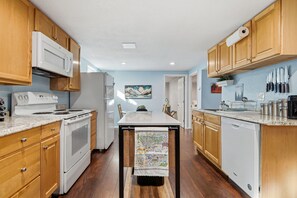 A kitchen with wooden cabinets, a white stove, and a dining area with a table.