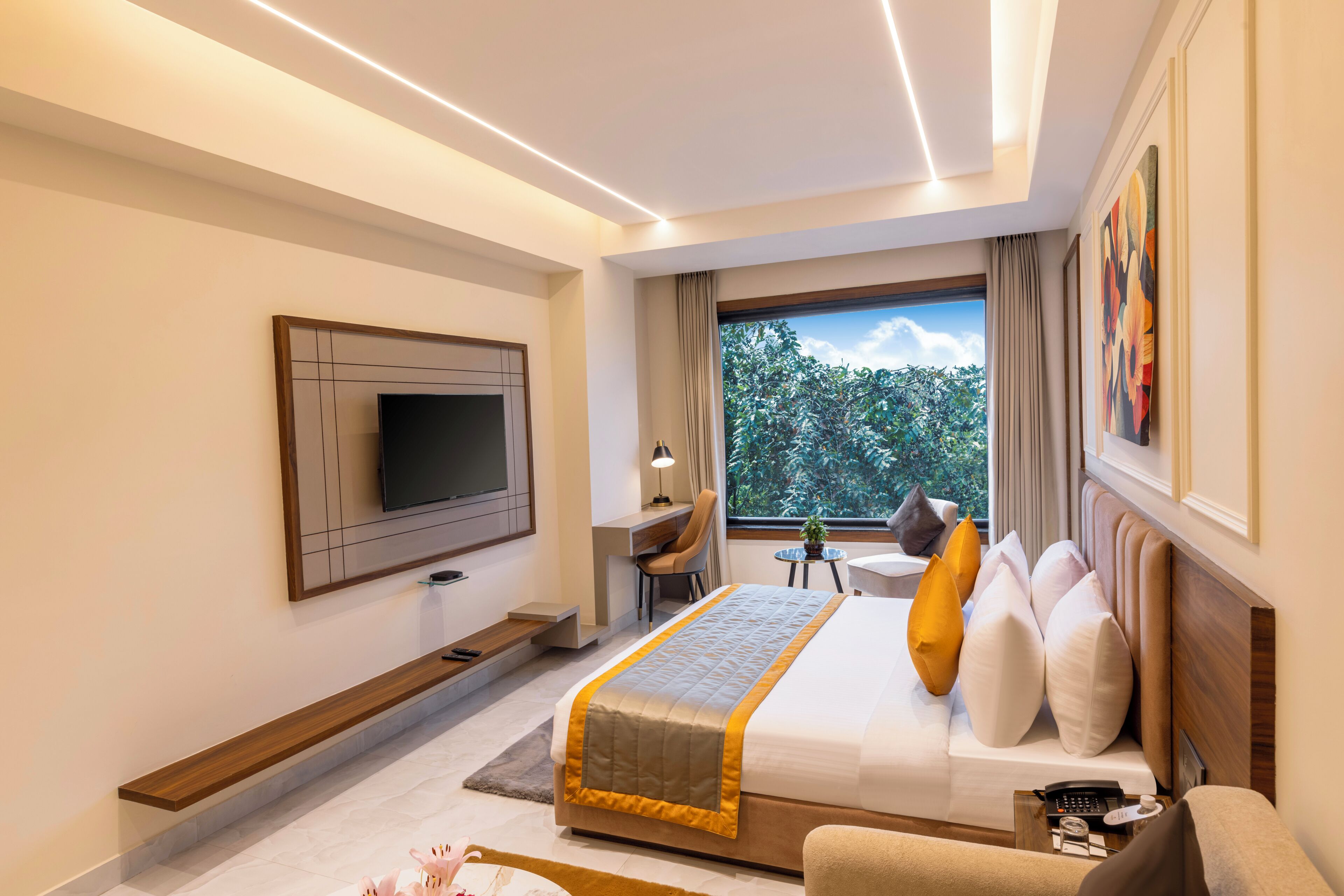 A modern hotel room with a bed, TV, desk, chair, and a view of the outdoors.