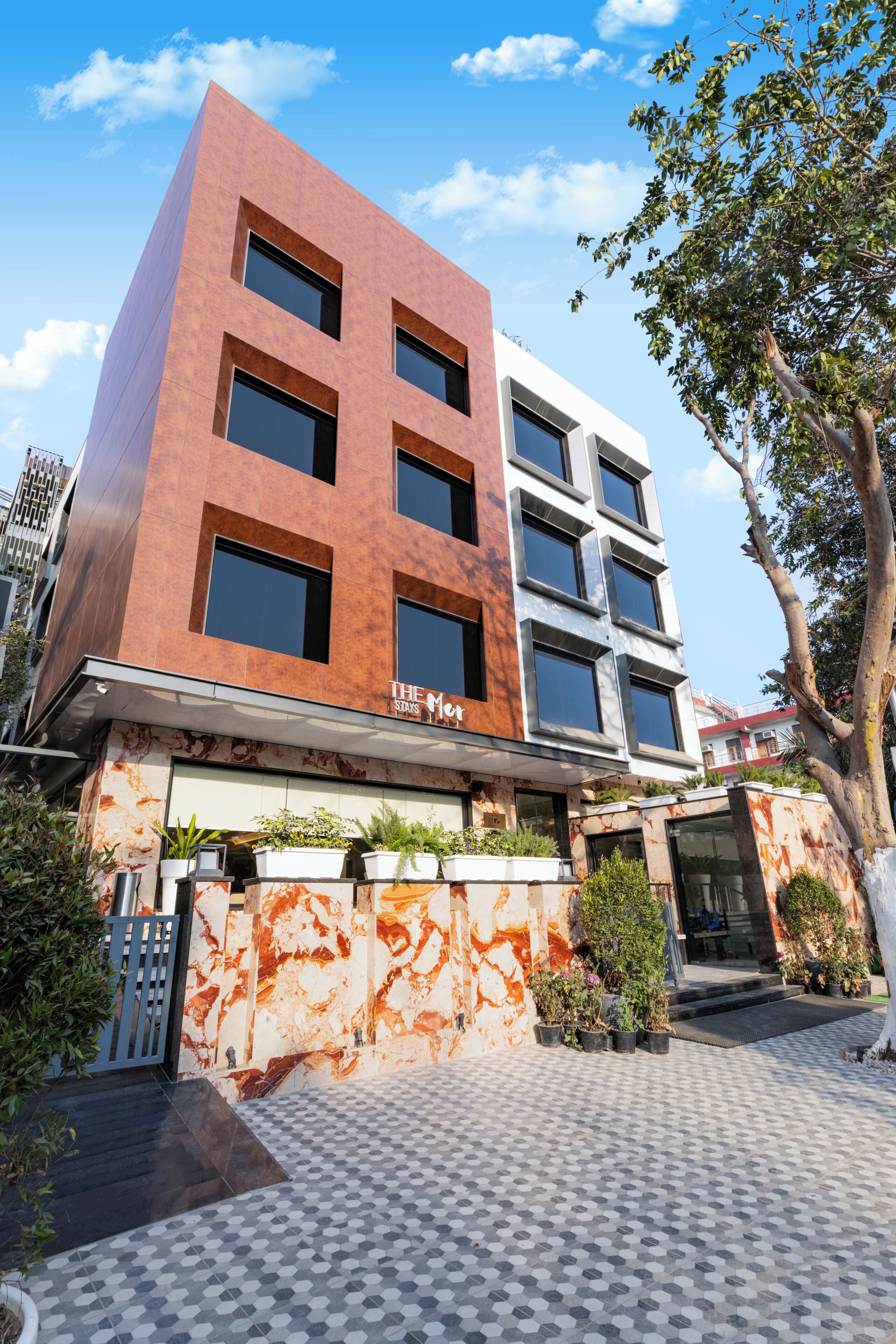 Un immeuble à plusieurs étages doté d’une architecture moderne, caractérisé par un mélange de façades en brique et en pierre blanche, de grandes fenêtres et un hall d’entrée carrelé.