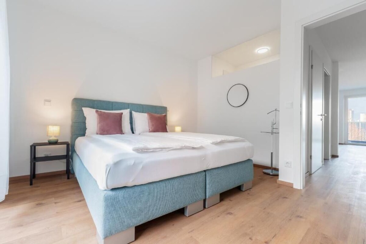 A modern bedroom with a bed, bedside tables, and a view of the outside.