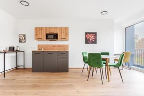 Une cuisine moderne avec des meubles en bois, un four à micro-ondes et un coin repas agrémenté de chaises vertes.