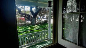 A porch with a white railing, a large tree, and a stained glass window.