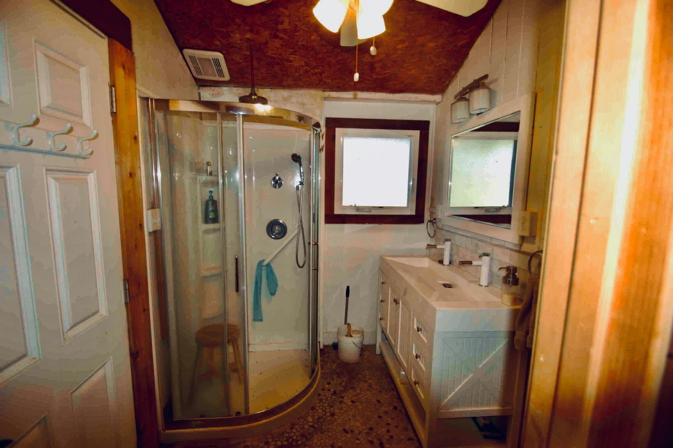 A compact bathroom with a glass shower enclosure, a sink, and a mirror.