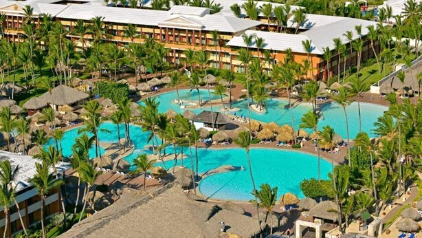 A resort with multiple swimming pools surrounded by palm trees and thatched umbrellas. - Iberostar Waves Punta Cana (Punta Cana)