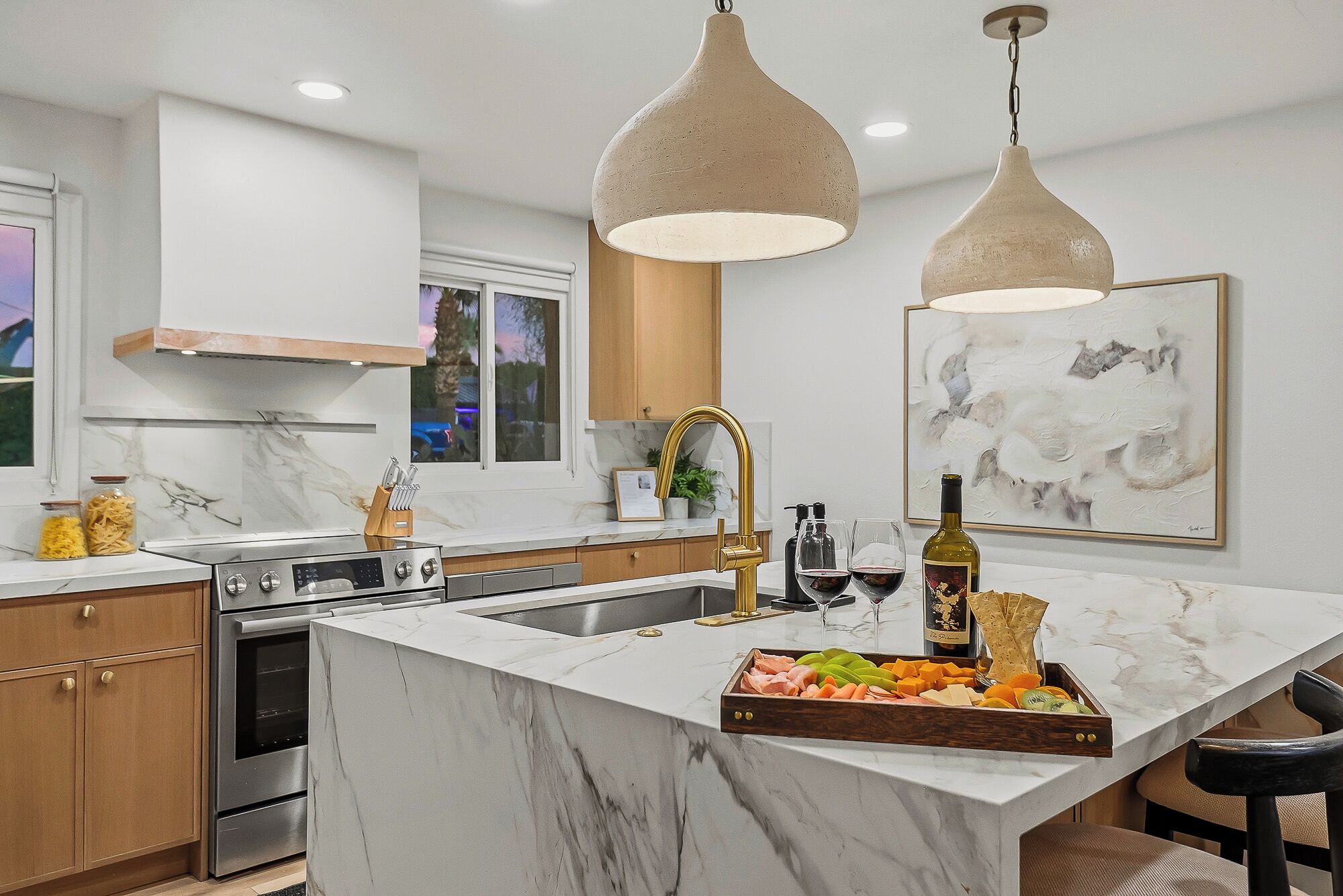 A modern kitchen with a marble island, stainless steel appliances, and pendant lighting.