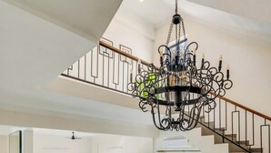 Una cocina amplia con electrodomésticos modernos, un comedor con mesa y sillas de madera, y una escalera con barandilla negra.