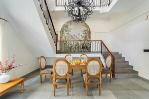 A dining area with a table set for six, surrounded by wooden chairs with woven backs.