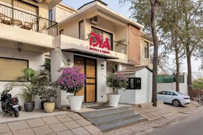 A hotel with a sign reading 'DIA HOTELS & RESORTS,' a balcony with chairs, and potted plants in front. - Vagator Maison by Dia Hotels and Homes (Anjuna)