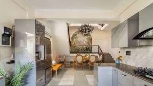 Una cocina moderna con zona de comedor, electrodomésticos de acero inoxidable y una escalera que conduce a un nivel superior.