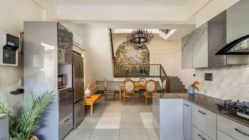 A modern kitchen with a dining area, stainless steel appliances, and a staircase leading to an upper level.