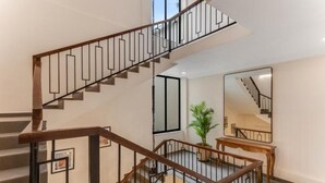 Una escalera moderna con barandas de madera y balaustres metálicos, que sube a un segundo piso.