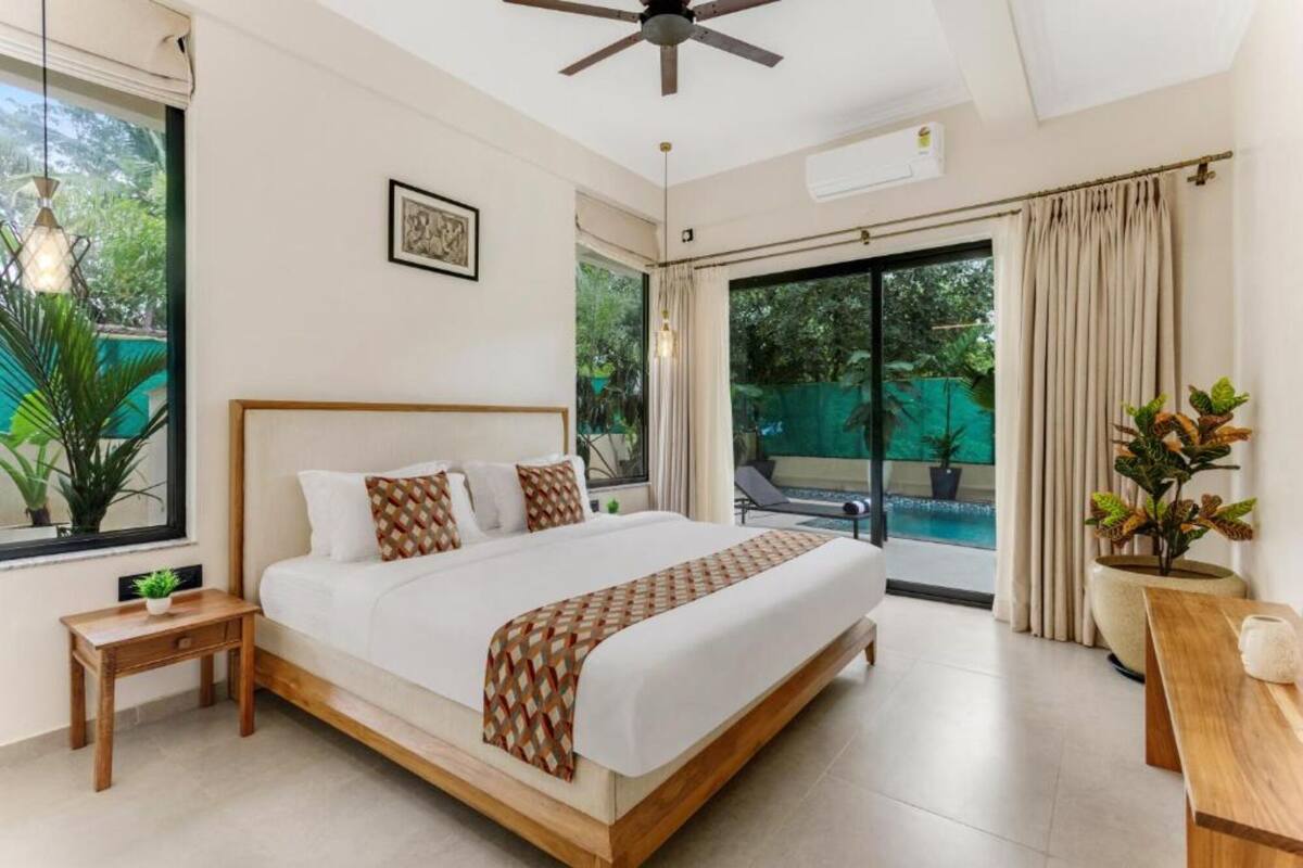 A modern hotel room with a large bed, a ceiling fan, and a view of a swimming pool.