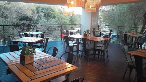 An outdoor dining area with wooden tables and chairs, surrounded by a railing. - Dainfern Luxury Penthouse (Midrand)