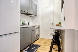 Una cocina compacta con electrodomésticos modernos, un pequeño comedor y piso de madera.