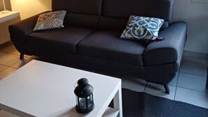 A modern living room with a dark grey sofa, patterned cushions, a white coffee table with a black lantern, and two wall-mounted paintings of a wolf and a deer. - A break in the countryside. If you want peace and quiet and authenticity, (Cirey)