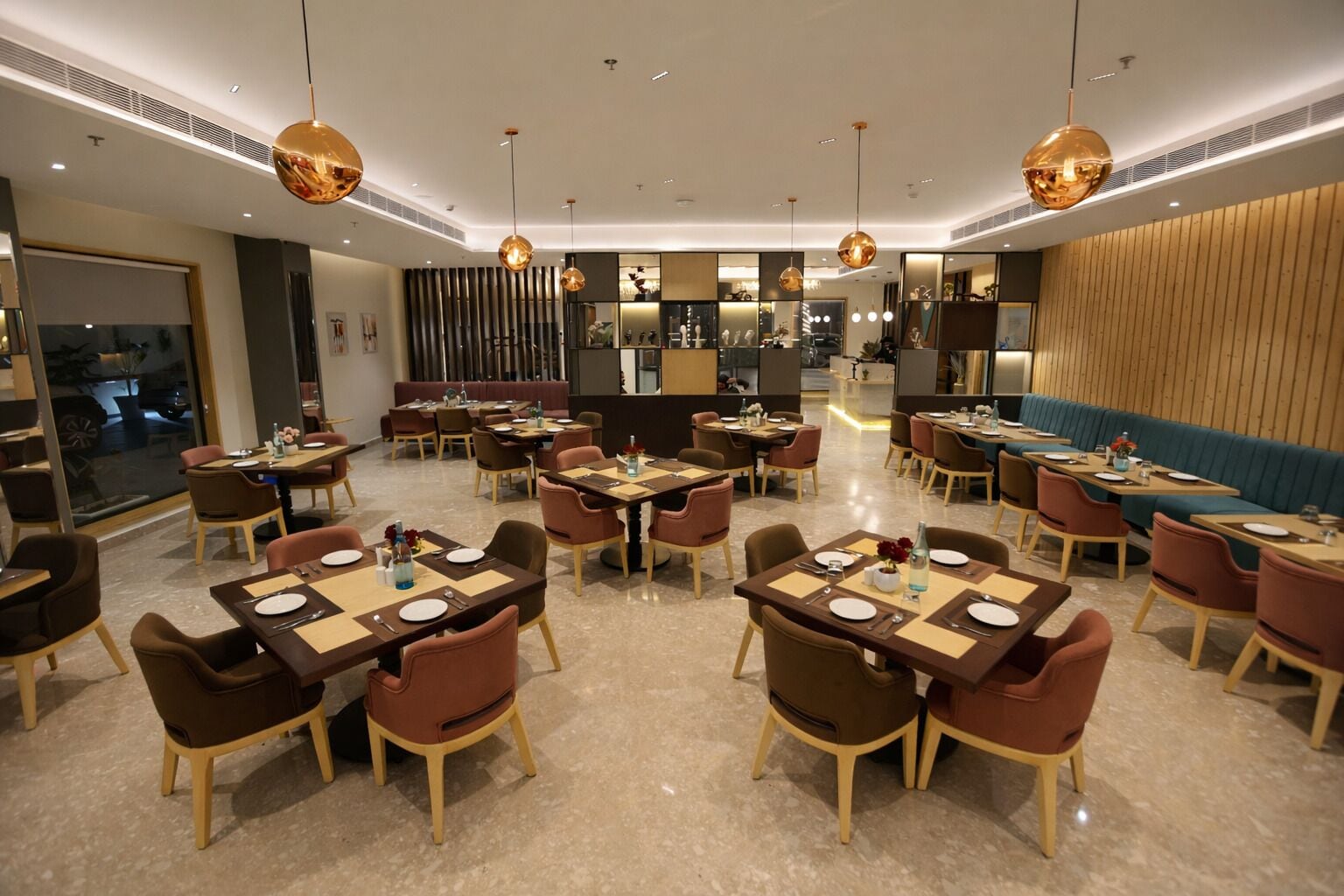 A modern dining area with multiple tables and chairs, a central bar area, and a view of the street outside.