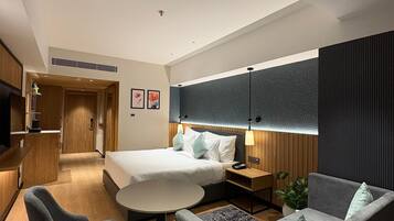 Una habitación de hotel moderna con una cama, un sofá, un escritorio y un televisor.