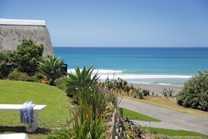 A coastal view with a grassy area, a bench, and a concrete wall.